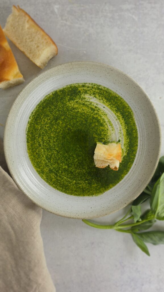 plate of basil oil with a piece of bread dredged through the basil oil