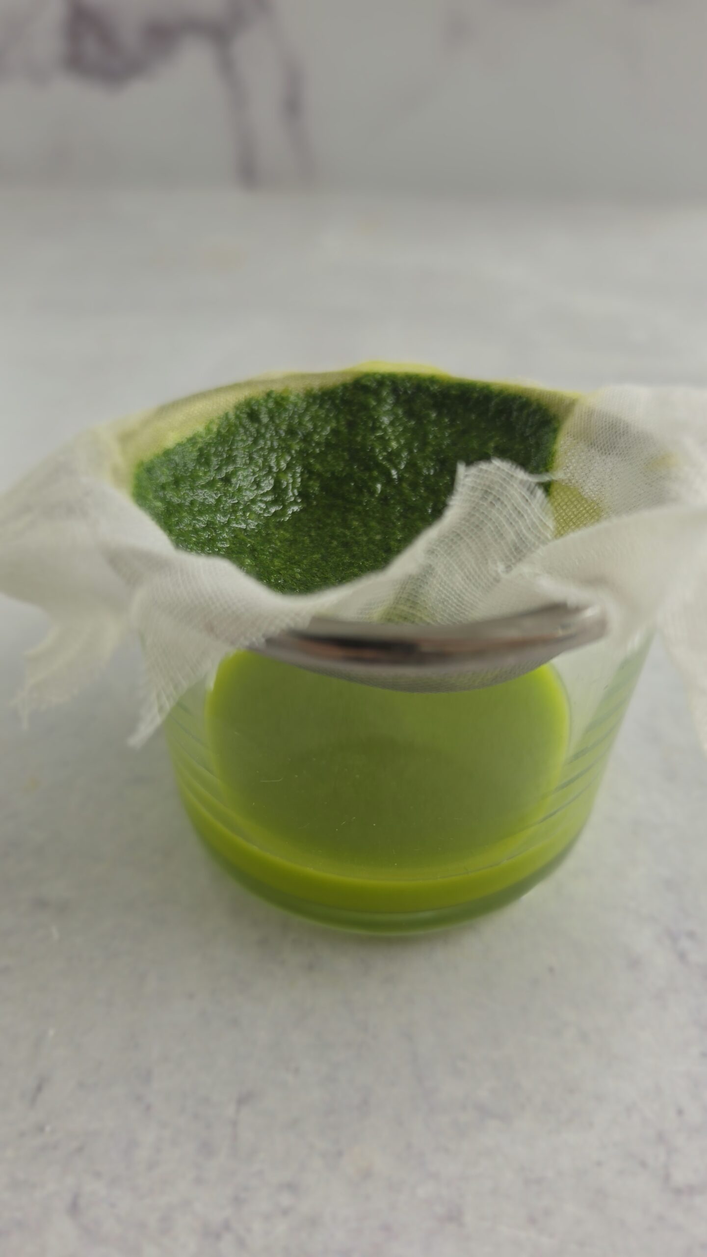 straining the basil through a cheesecloth for basil oil