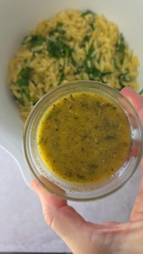 adding Italian salad dressing to the cooked orzo and spinach