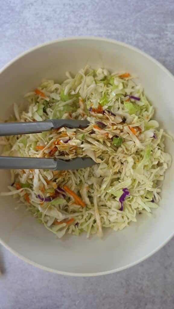starting to mix the dressing into the cabbage mix for the sesame ginger slaw
