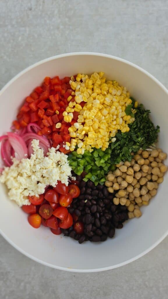 mixing bowl with all the ingredients for dense bean salad