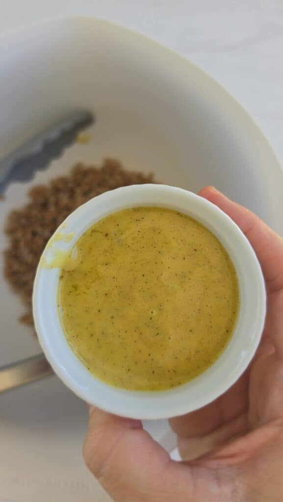 adding lemon vinaigrette to the cooked farro