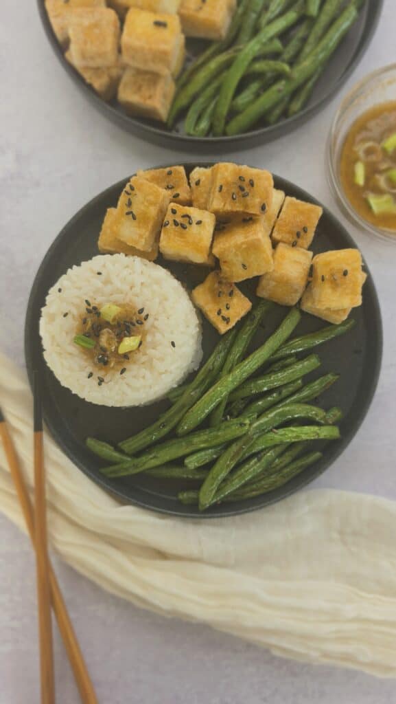 plate of crispy pan fried tofu with rice, roasted green beans, and sesame sauce