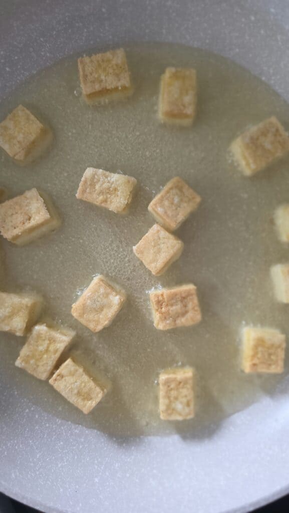 tofu cubes cooking in a sauté pan starting to brown on a few sides