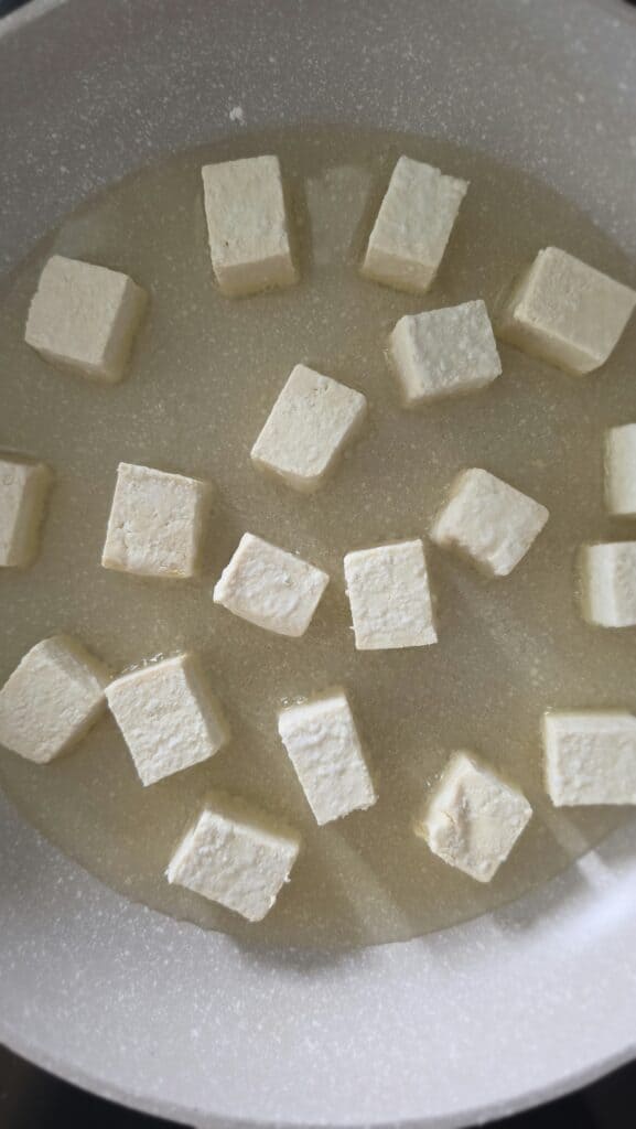 oil in a sauté pan with tofu cubes starting to cook