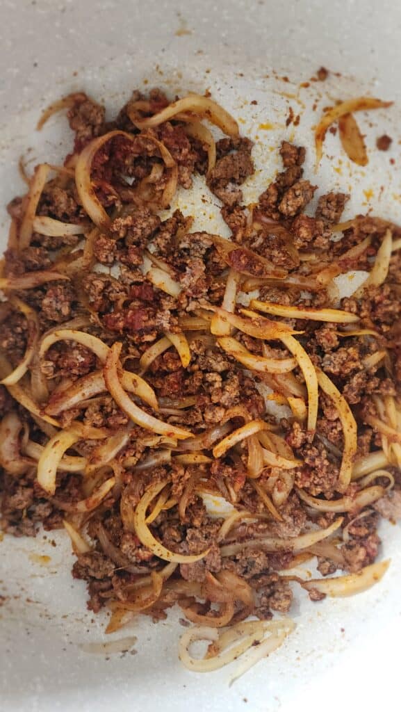 adding tomato paste in to the cooked ground beef